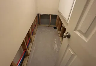 Unfinished basement bathroom during renovation with exposed framing and concrete floor