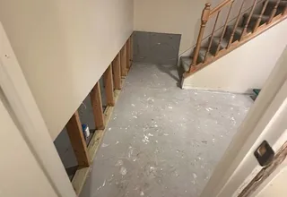Basement stairwell prepped for drywall with open framing and bare concrete floor
