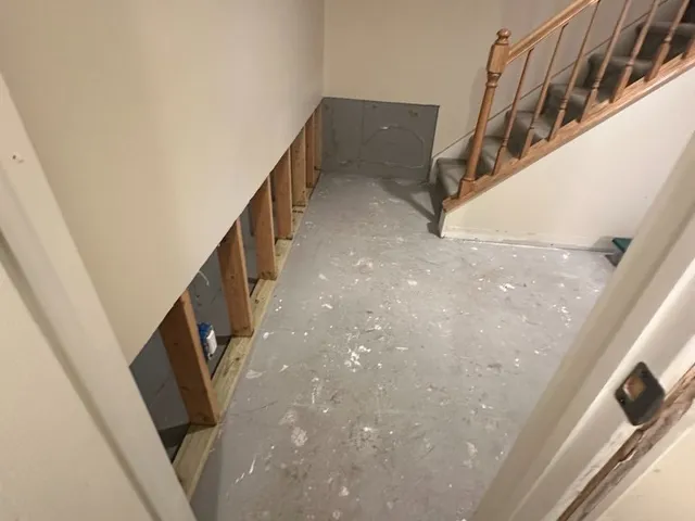 Basement stairwell prepped for drywall with open framing and bare concrete floor