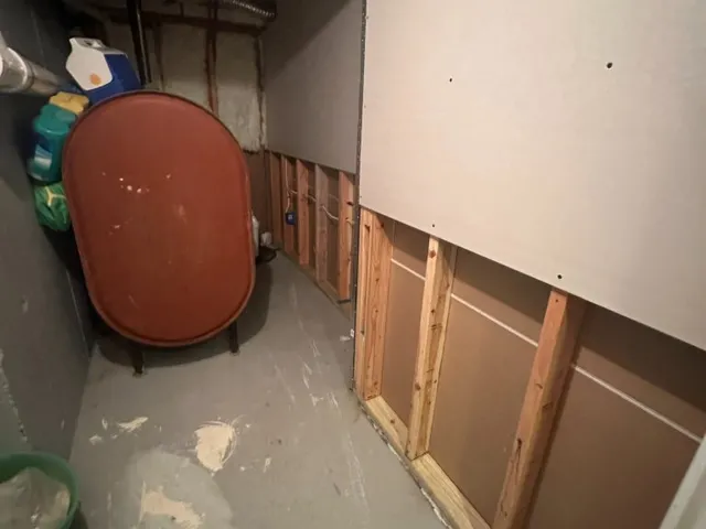 Basement utility area mid-project with new drywall panel over exposed framing