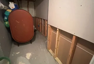 Basement utility area mid-project with new drywall panel over exposed framing