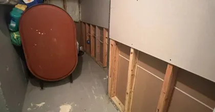 Basement utility area mid-project with new drywall panel over exposed framing