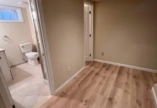 Painted basement room with beige walls opening to a finished bathroom