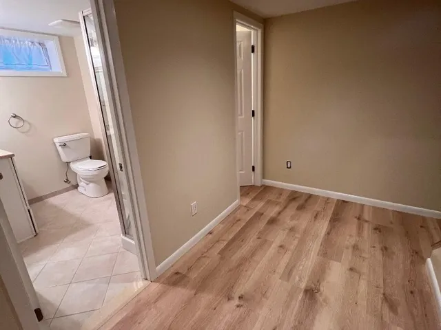 Painted basement room with beige walls opening to a finished bathroom