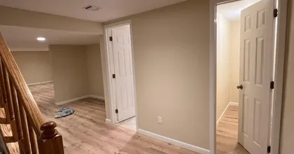 Freshly painted basement hallway with white six-panel doors and warm beige walls