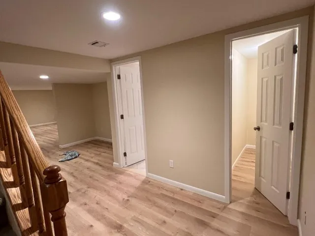 Freshly painted basement hallway with white six-panel doors and warm beige walls