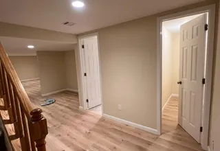 Freshly painted basement hallway with white six-panel doors and warm beige walls