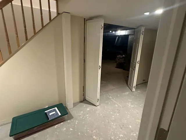 Painted basement landing with white bi-fold doors under a wood staircase