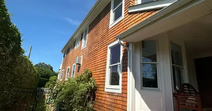 Cedar shake home with white trim and covered front porch on a sunny day