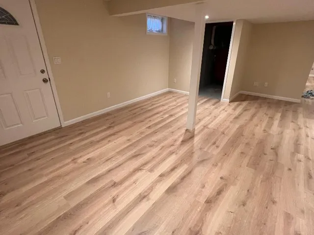 Finished basement with fresh beige walls and new light wood-look flooring