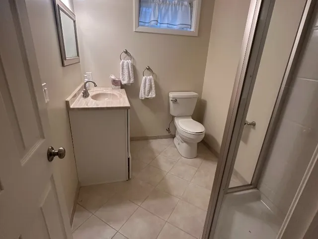 Freshly painted beige basement bathroom with vanity, toilet and glass shower