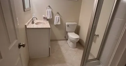 Newly painted basement bathroom with tan walls, tile floor and shower stall