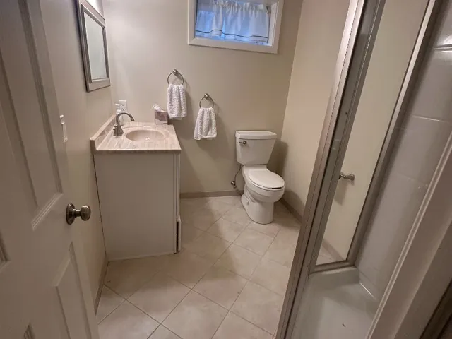 Newly painted basement bathroom with tan walls, tile floor and shower stall