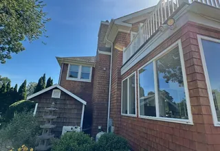 Cedar shingle home exterior with white-trimmed windows under a bright blue sky
