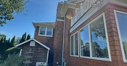 Cedar shingle home exterior with white-trimmed windows under a bright blue sky