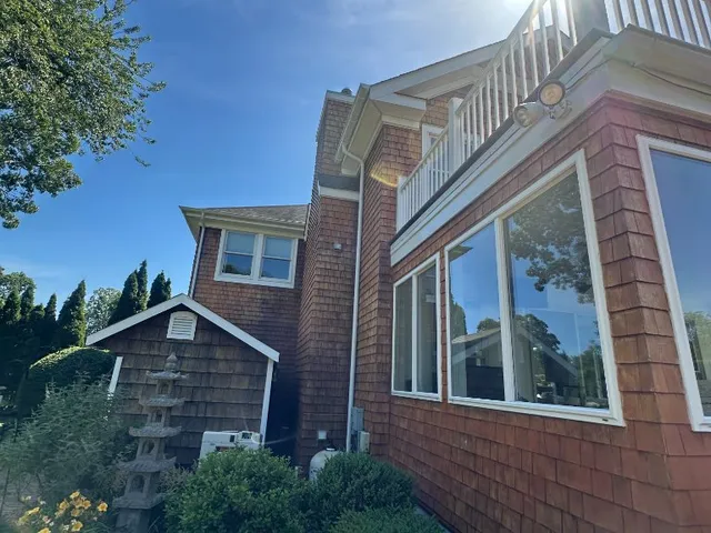 Cedar shingle home exterior with white-trimmed windows under a bright blue sky
