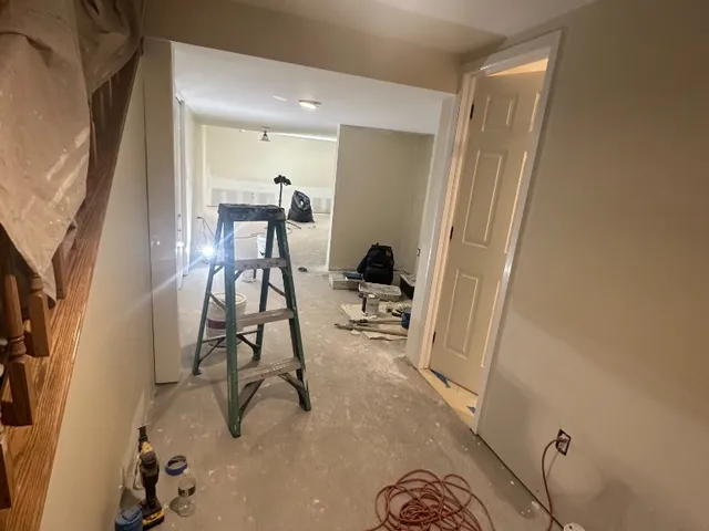 Interior painting job in progress with ladder, drop cloths and masked walls