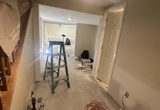 Interior painting job in progress with ladder, drop cloths and masked walls