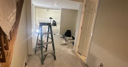 Interior painting job in progress with ladder, drop cloths and masked walls