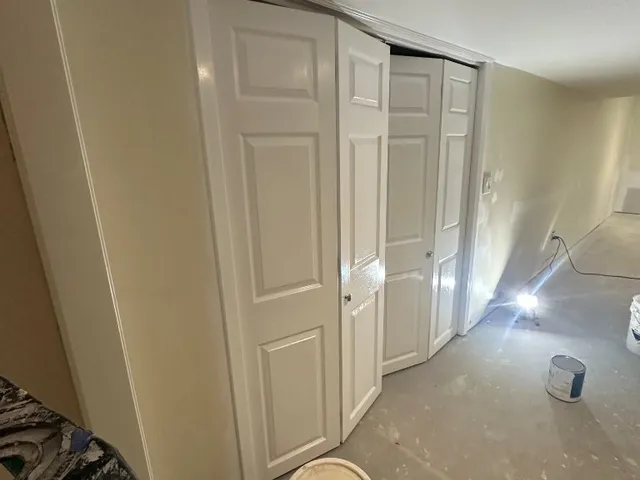 Freshly painted white six-panel closet doors and trim during an interior job