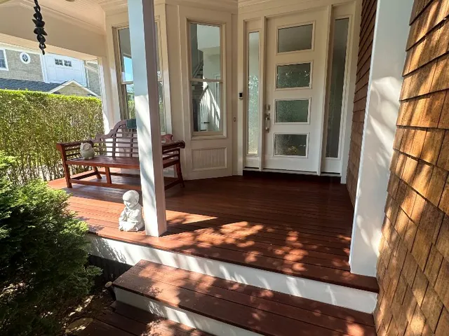 Front porch with richly stained mahogany decking, white columns and cedar shingles