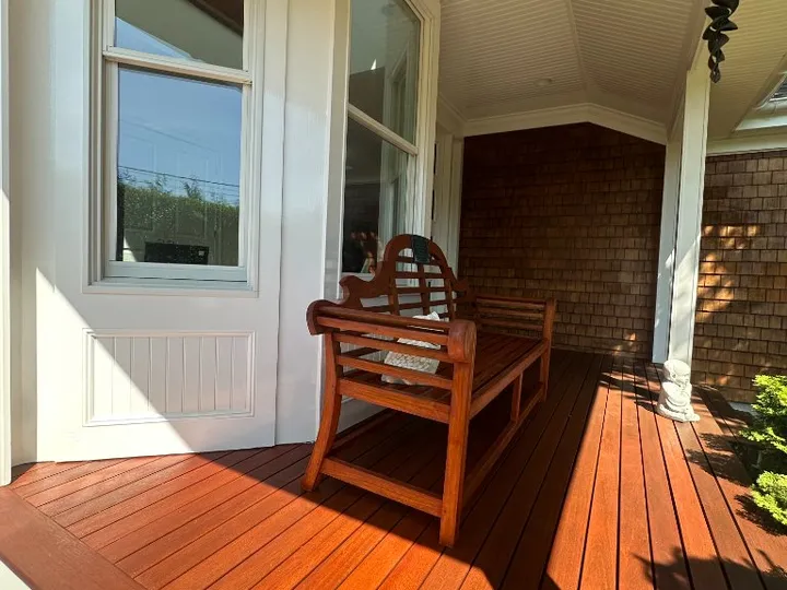 Sunny porch with freshly stained wood deck and a wooden bench