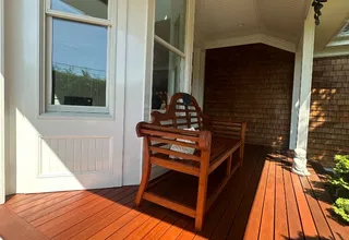 Sunny porch with freshly stained wood deck and a wooden bench