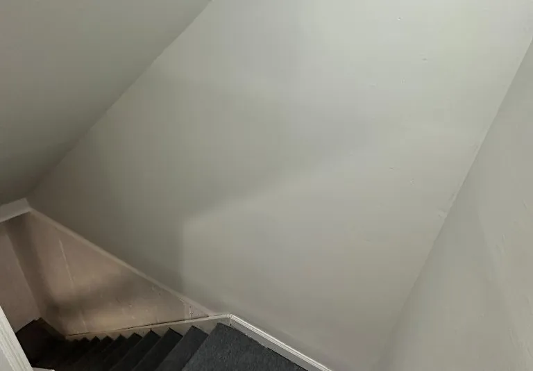 Smooth freshly painted stairwell walls after spackling and priming